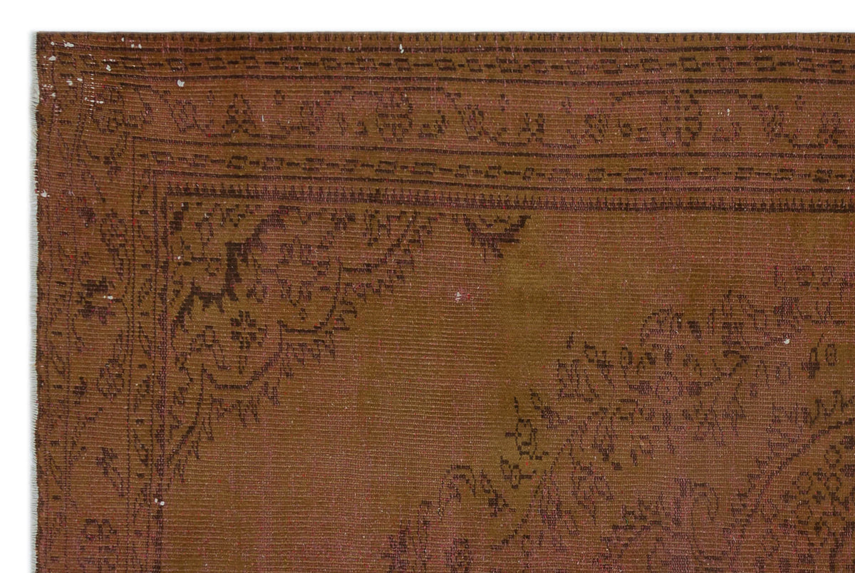 Brown vintage-style rug with a dark, faded floral medallion pattern and a geometric border.