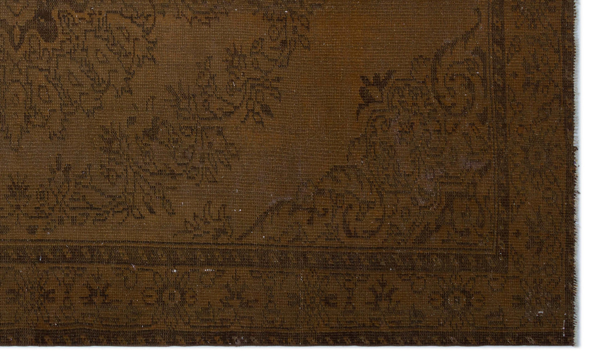 Dark brown rug with a tonal, distressed floral medallion pattern and a detailed border.