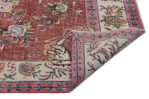 Load image 1 in gallery view. Distressed terracotta and cream rug with a floral medallion pattern and a folded corner, isolated on a white background.