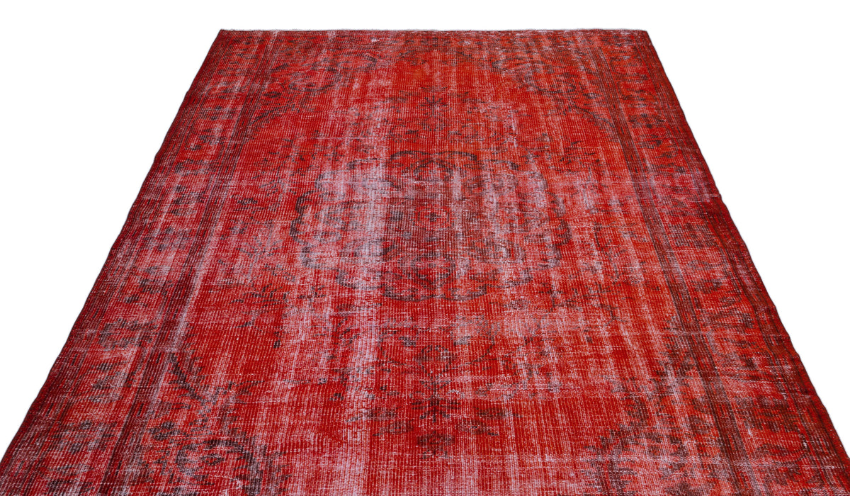 Distressed red vintage-style rug with a faded central medallion and dark grey intricate patterns.
