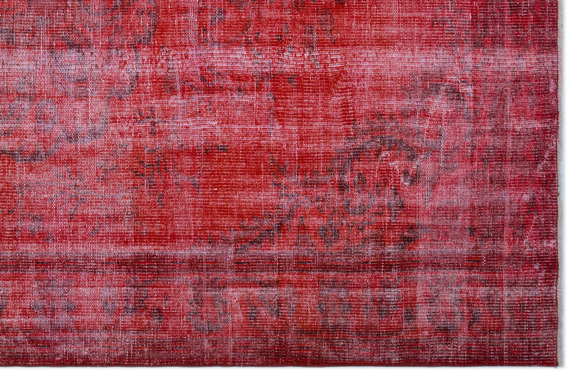 Distressed red and dark pink overdyed rug with a faded traditional medallion pattern.