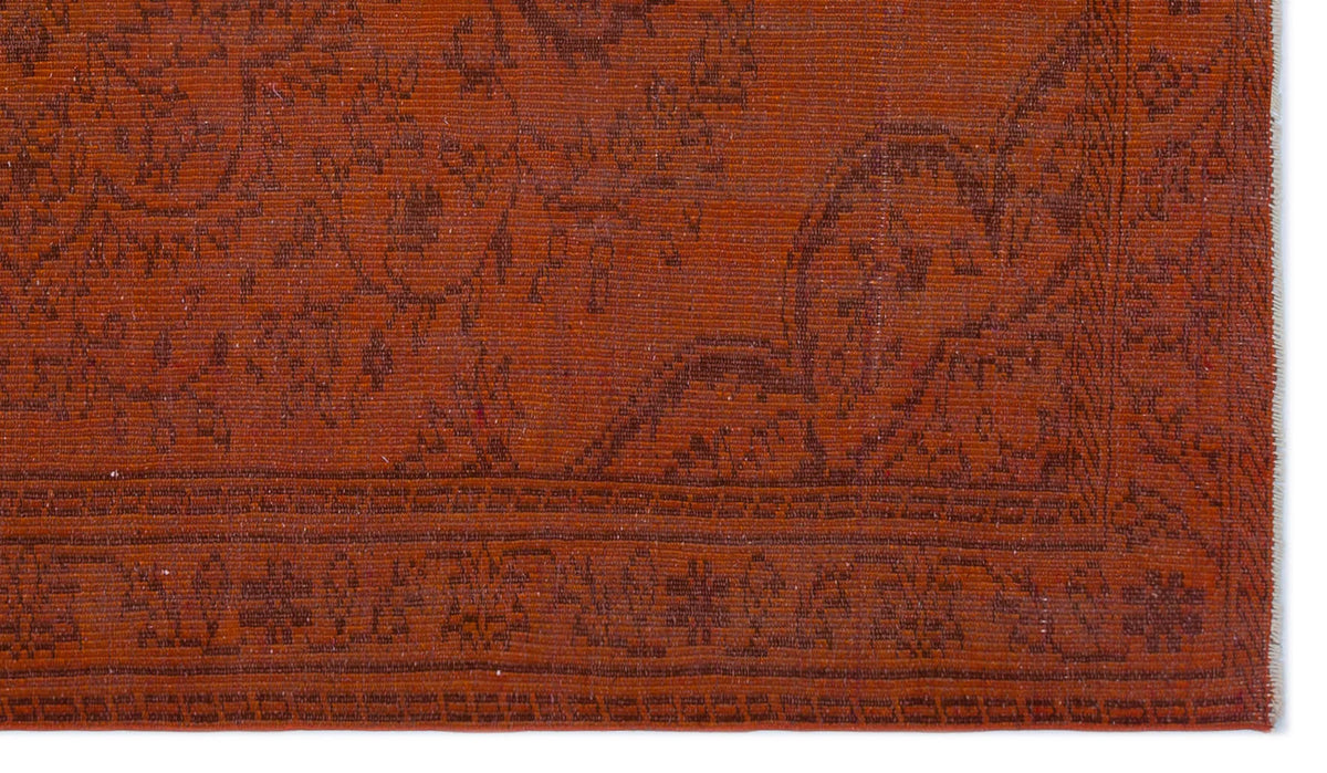 Rust-colored rug with a dark brown traditional floral pattern and a geometric border.