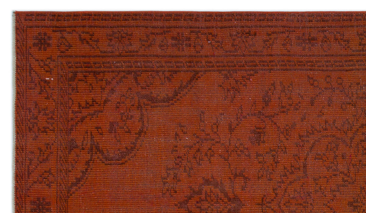 Rust-colored rug with a dark brown, subtle floral and geometric border pattern.