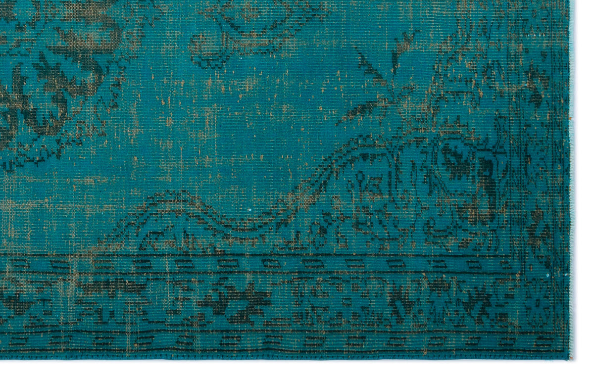 Teal and dark brown rug with a distressed traditional floral medallion pattern and a geometric border.