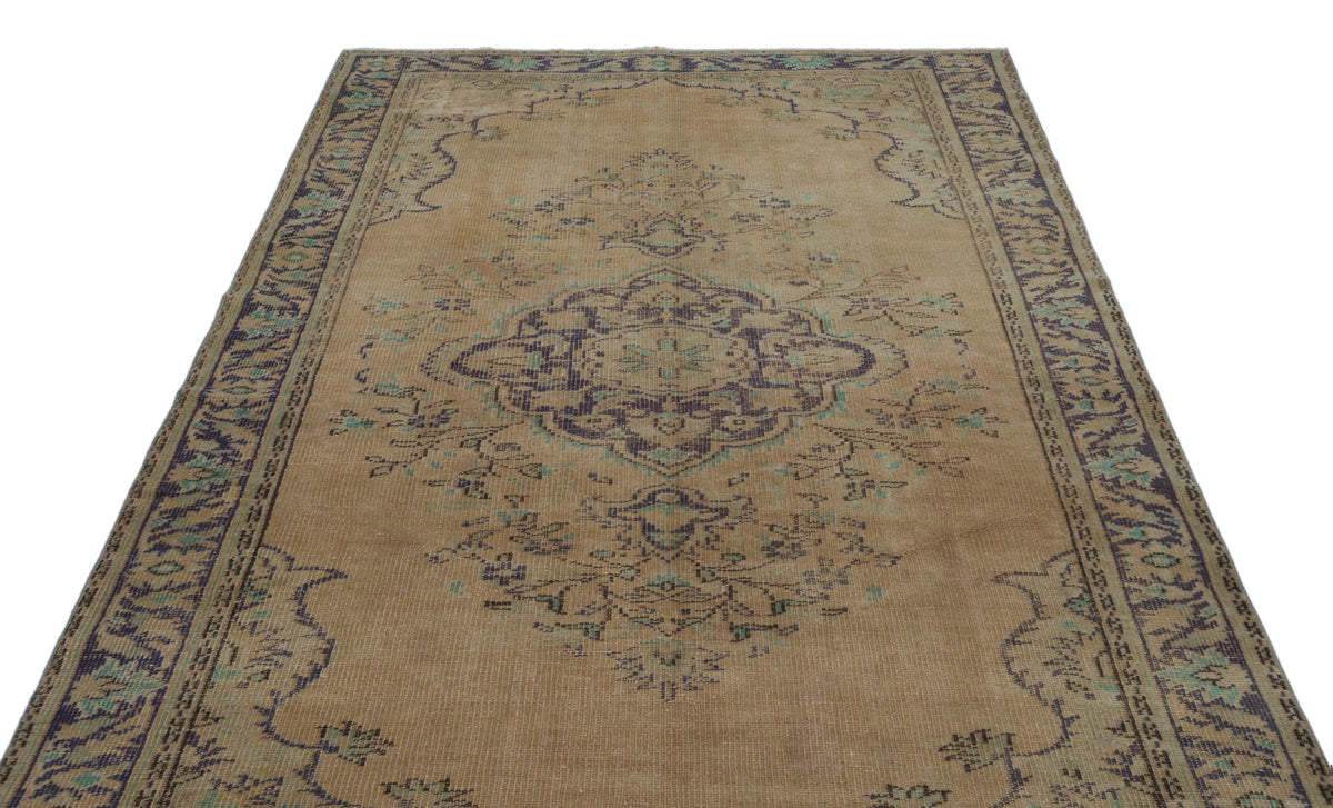 Tan vintage-style rug with a dark purple and teal central medallion and ornate border on a white background.