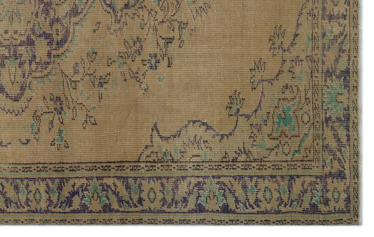 Tan vintage-style rug with a distressed floral medallion pattern in dark blue and teal accents.