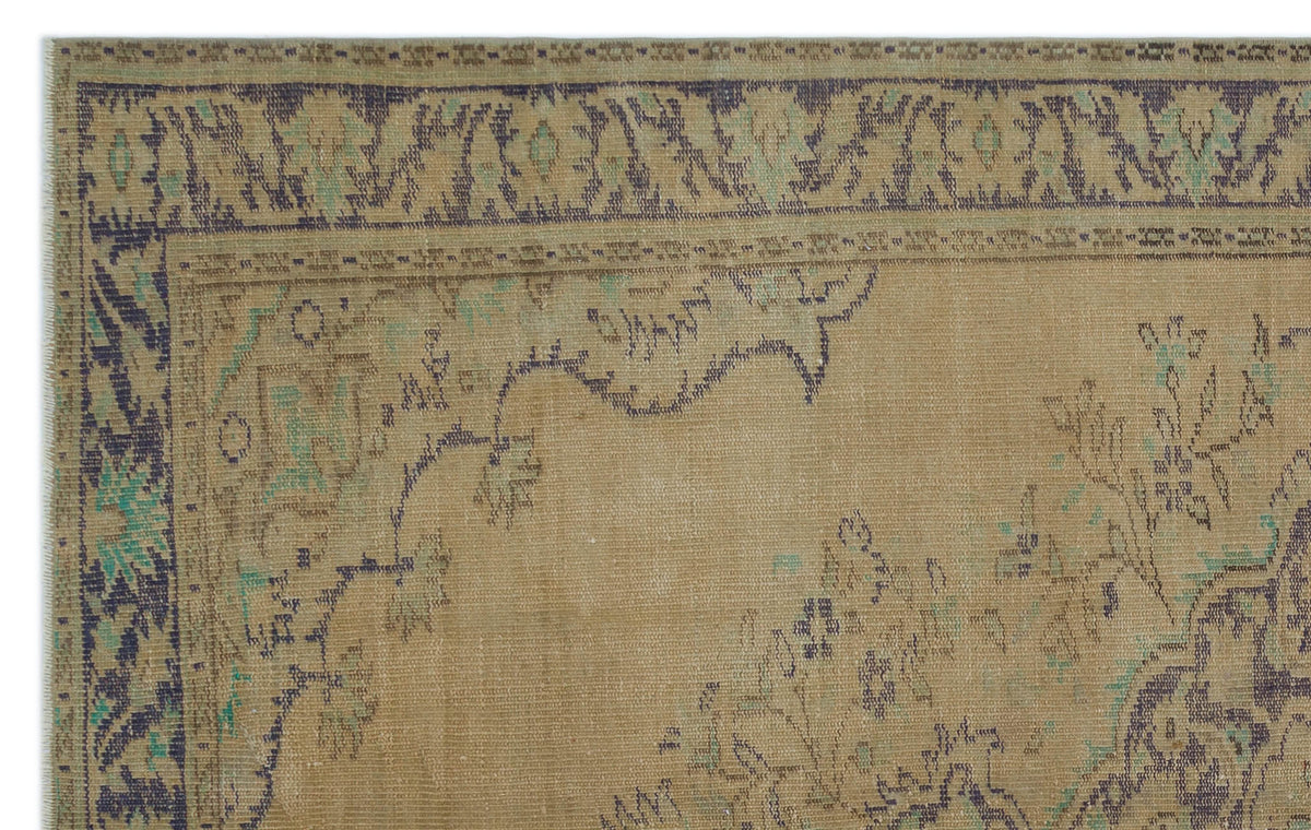 Tan vintage-style rug with a distressed dark blue and teal floral border and central medallion pattern.