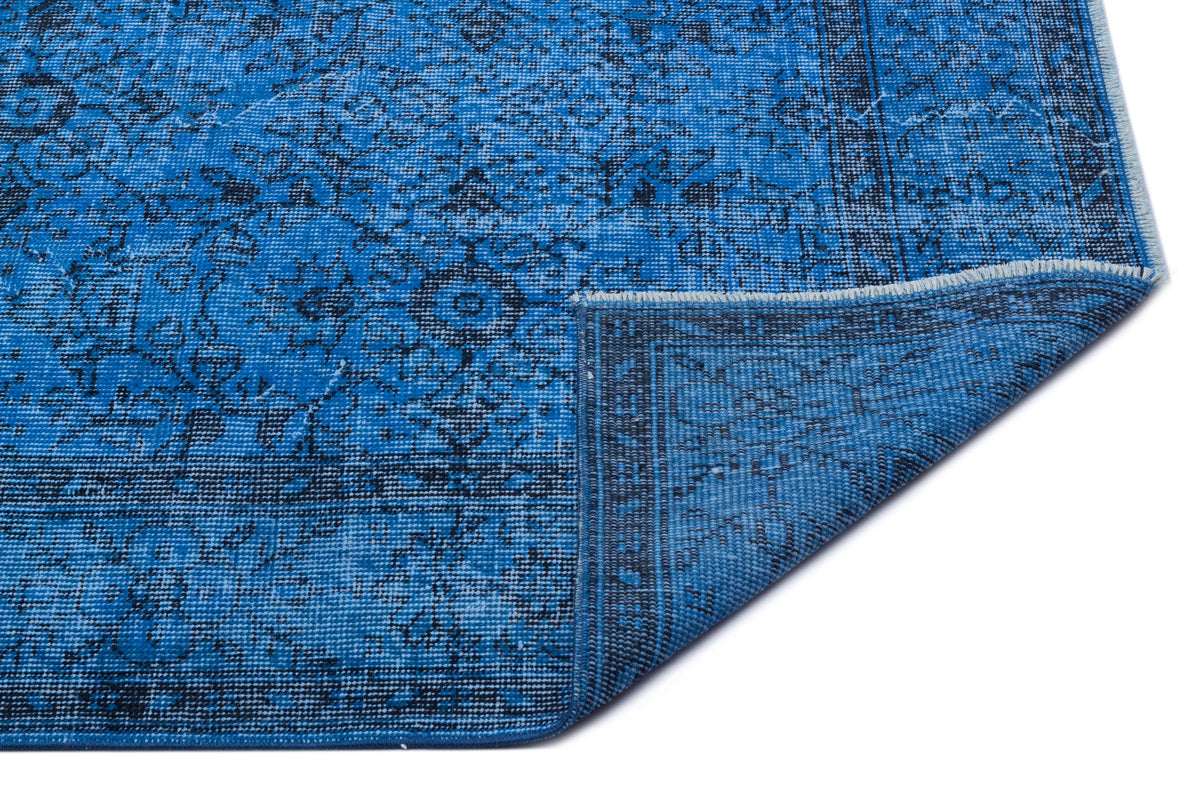 Bright blue rug with a distressed traditional floral pattern and a folded corner, isolated on a white background.