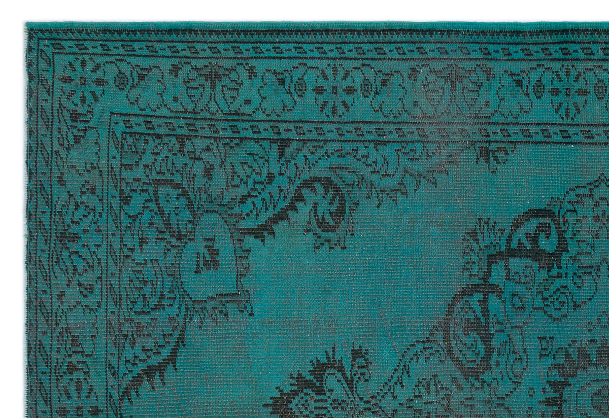 Teal and black rug with a traditional distressed floral medallion pattern and a geometric border.