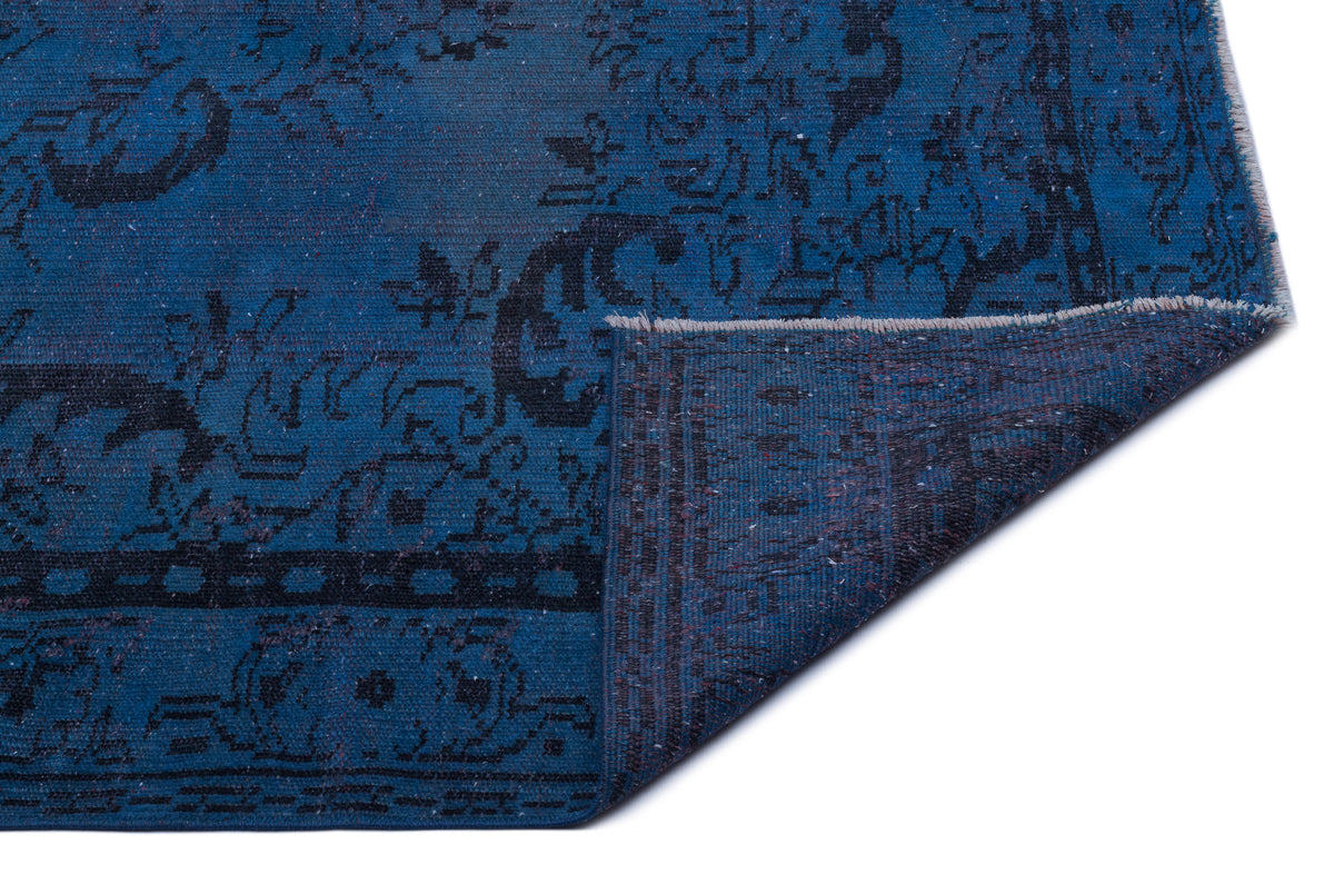 Blue and black distressed traditional rug with a folded corner revealing the textured backing.