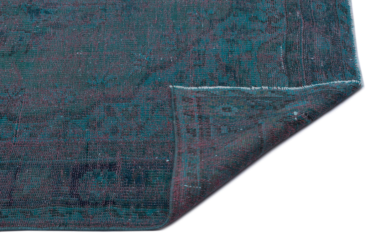 Teal and dark purple distressed vintage-style rug with a folded corner on a white background.