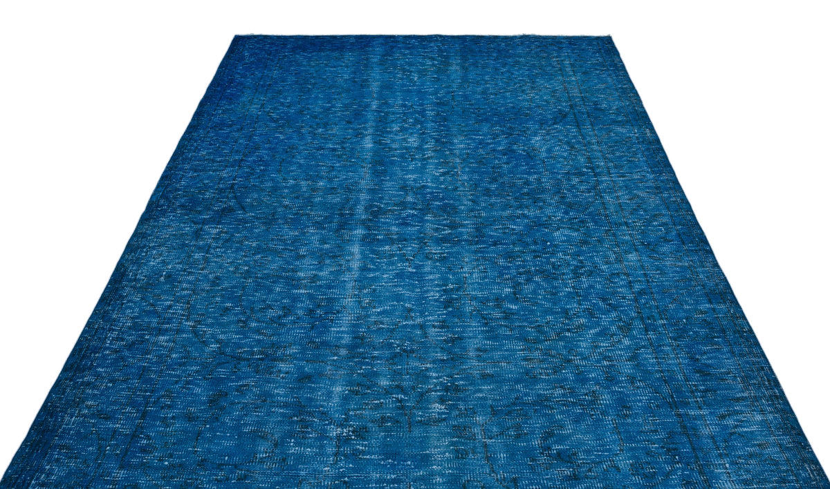 Solid blue vintage-style rug with a distressed, faded texture and subtle dark geometric border details.