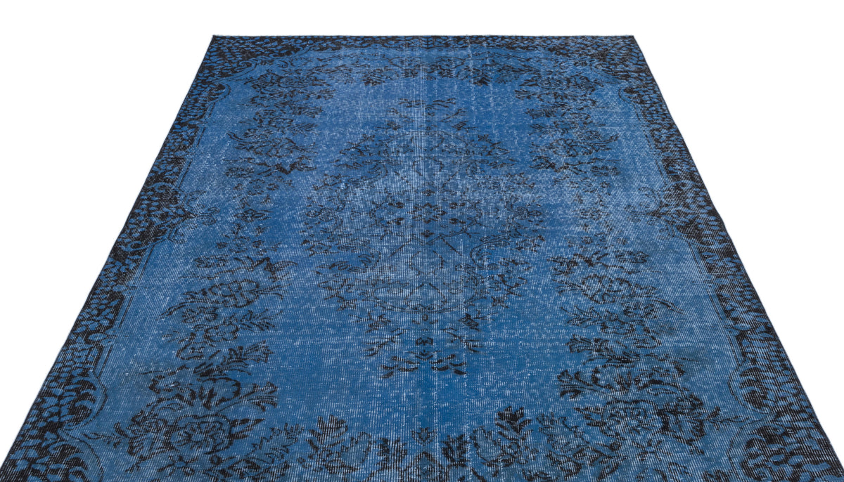 Blue and black distressed rug with a traditional floral medallion pattern on a white background.