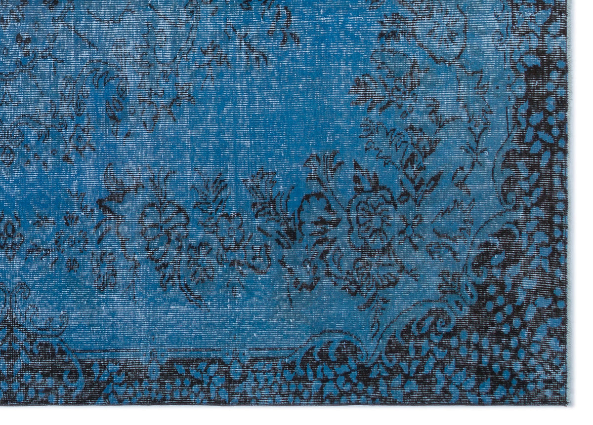 Bright blue rug with a distressed black floral medallion pattern and a dark decorative border.