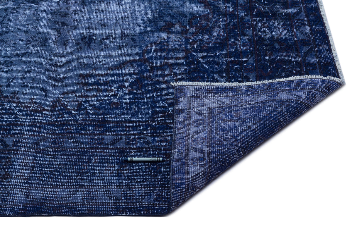 Navy blue distressed traditional rug with a folded corner revealing the underside, isolated on a white background.