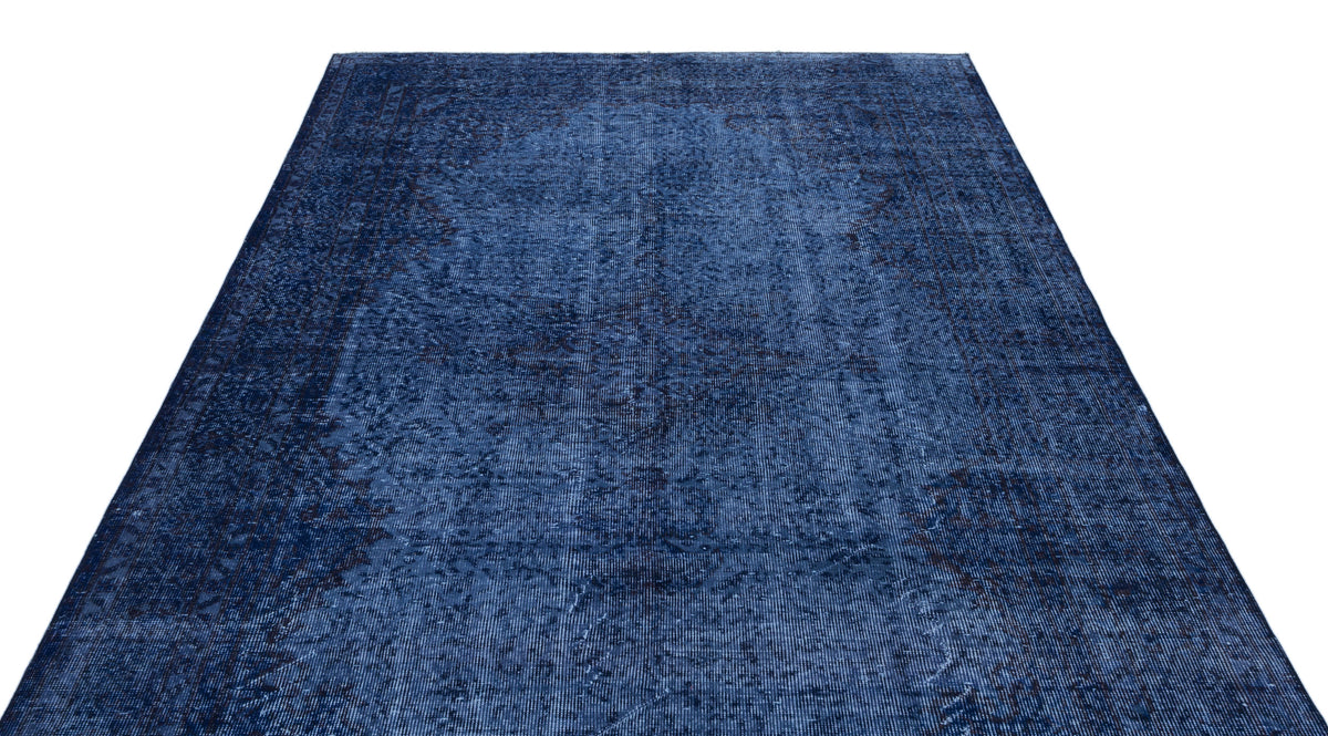 Monochromatic navy blue rug with a distressed, traditional medallion pattern on a white background.
