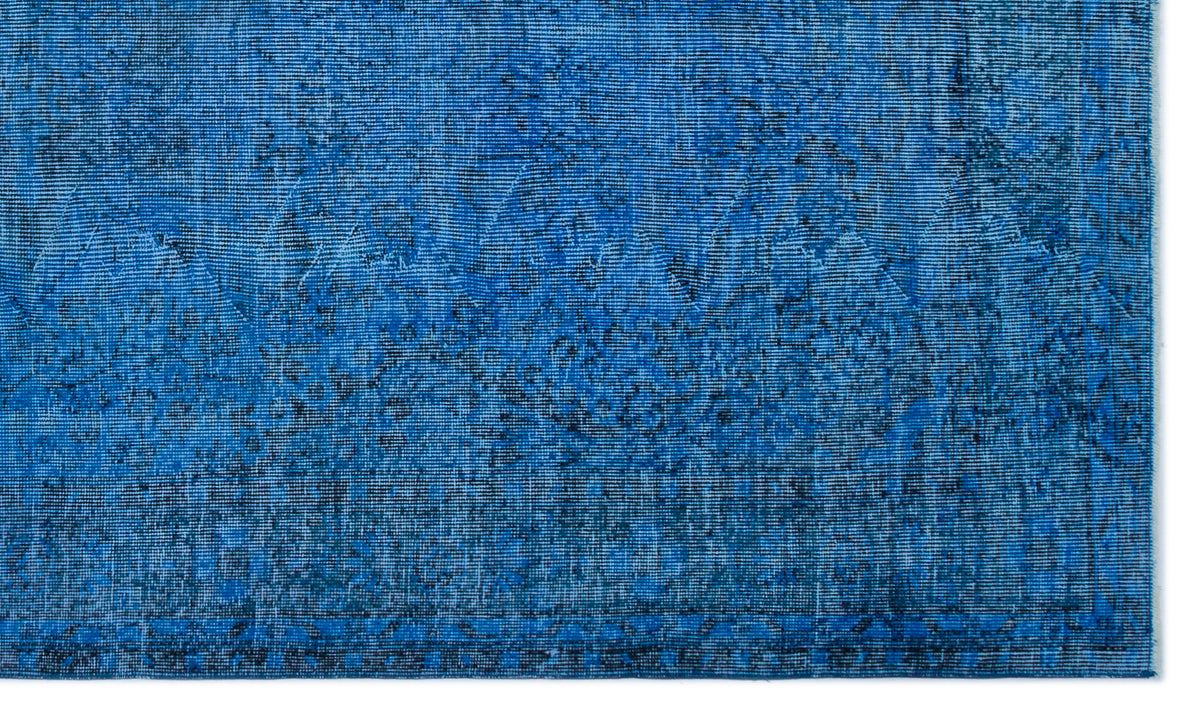 Bright blue distressed rug with a subtle, faded geometric medallion pattern and dark navy textured detailing.