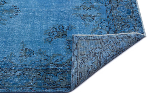 Load image 1 in gallery view. Bright blue distressed rug with a dark grey floral medallion pattern and a folded corner on a white background.