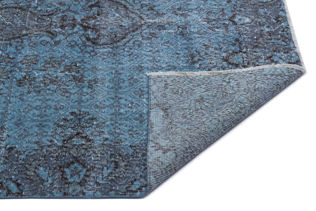 Blue and charcoal distressed traditional medallion rug with a folded corner showing the woven backing.