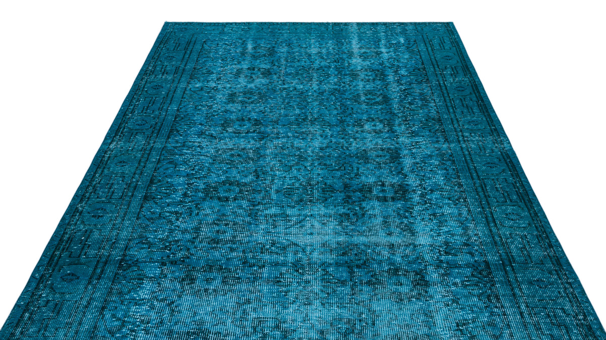 Teal distressed traditional area rug with a faded ornate medallion pattern and a geometric border.