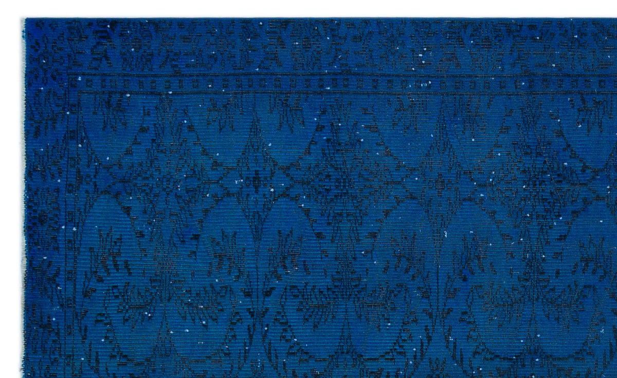 Deep blue rug with a black geometric diamond and floral medallion pattern and a distressed finish.