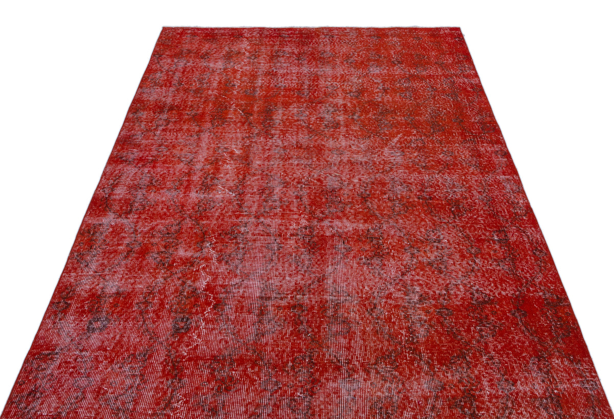 Distressed red rug with a faded, intricate traditional pattern on a white background.