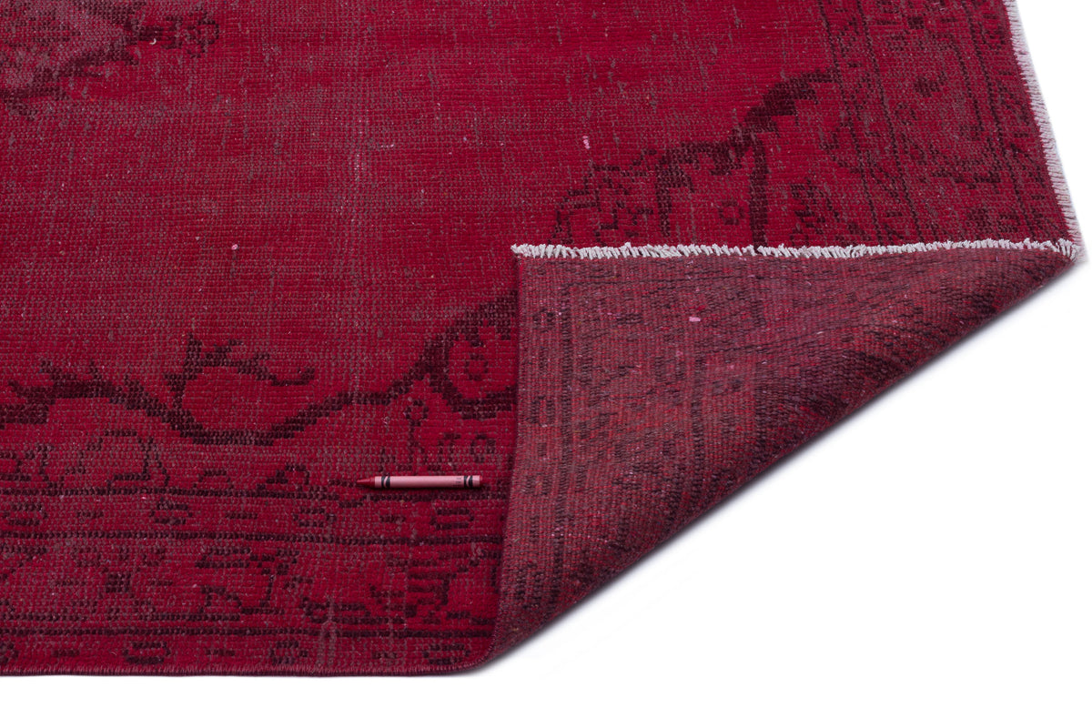 Deep red vintage-style rug with a dark, distressed floral pattern and a folded corner showing the underside.