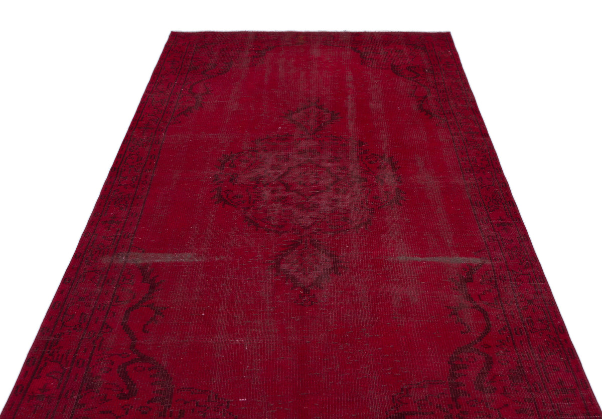 Deep red vintage-style rug with a distressed black central medallion and ornate border pattern on a white background.