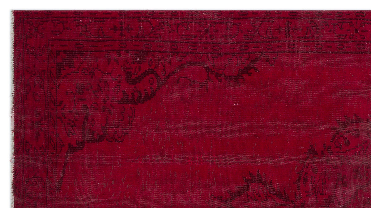 Deep red rug with a black distressed floral medallion pattern and a geometric border.