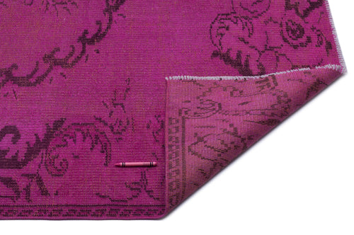 Load image 1 in gallery view. Magenta rug with a dark purple floral medallion pattern and a folded corner showing the underside.