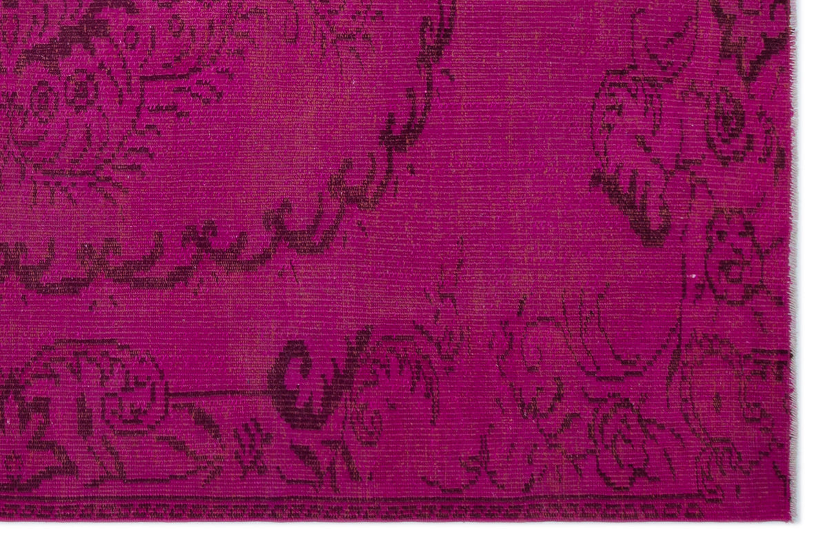 Magenta rug with a dark, distressed floral medallion pattern and a textured, woven finish.