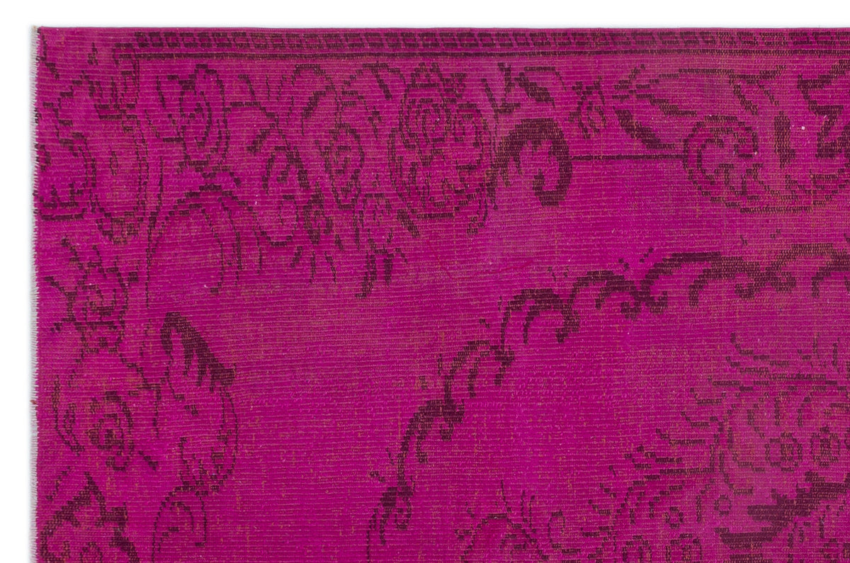 Magenta rug with a dark purple overdyed floral medallion pattern and a geometric border.