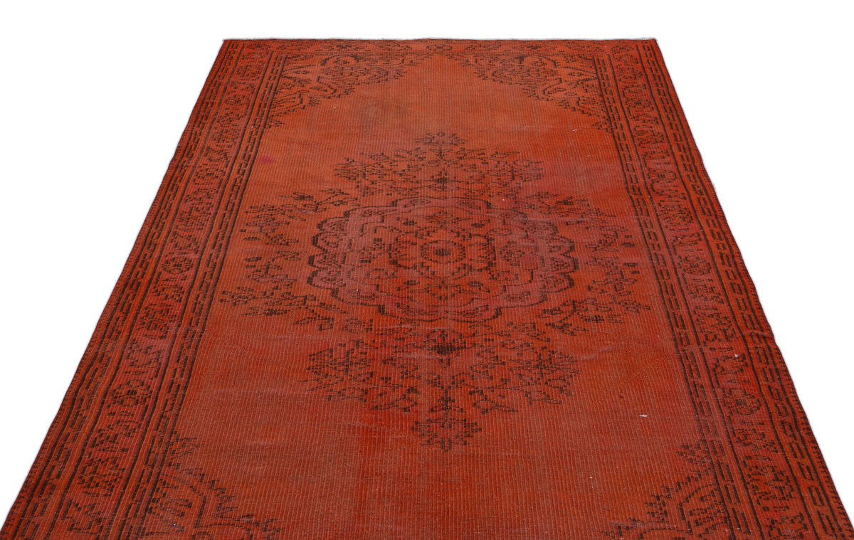 Distressed terracotta rug with a dark brown central floral medallion and geometric border on a white background.