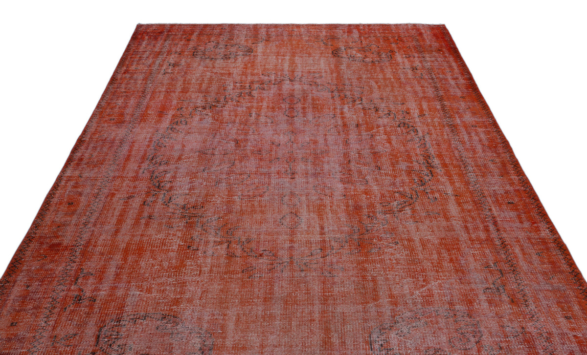 Distressed terracotta and rust-colored rug with a faded central medallion and dark grey intricate border details.