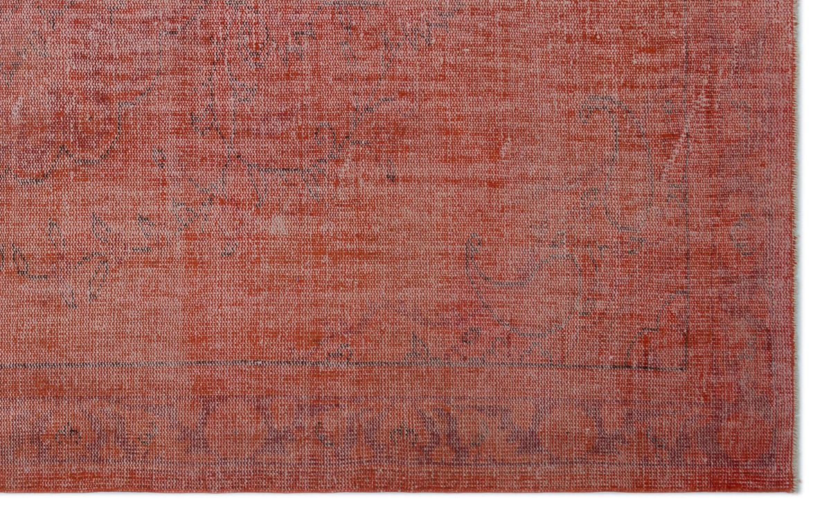 Distressed terracotta red rug with a faint, faded traditional floral pattern and a dark border.