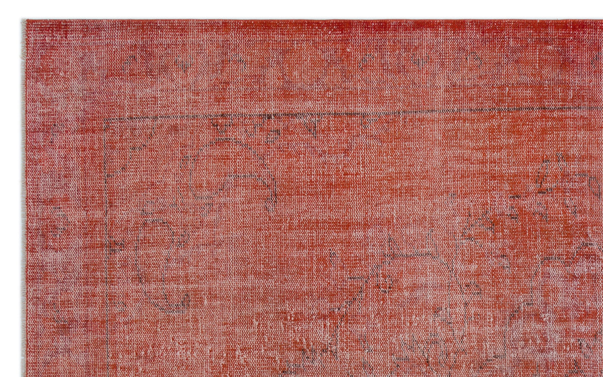 Distressed terracotta red rug with a faint, faded black traditional medallion pattern.