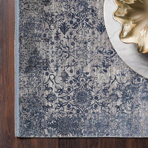 Load image 1 in gallery view. Navy and grey distressed floral medallion rug on a dark wood floor with a marble side table.