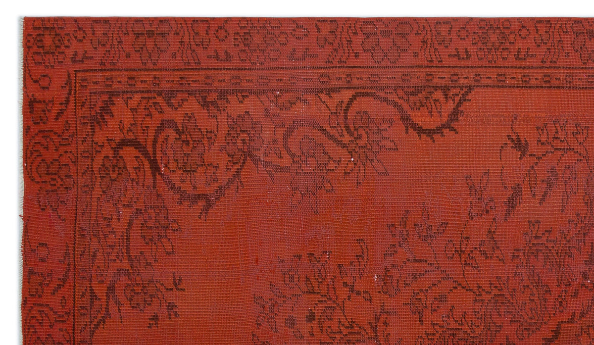 Terracotta red rug with a dark brown floral border and intricate vine-like patterns.
