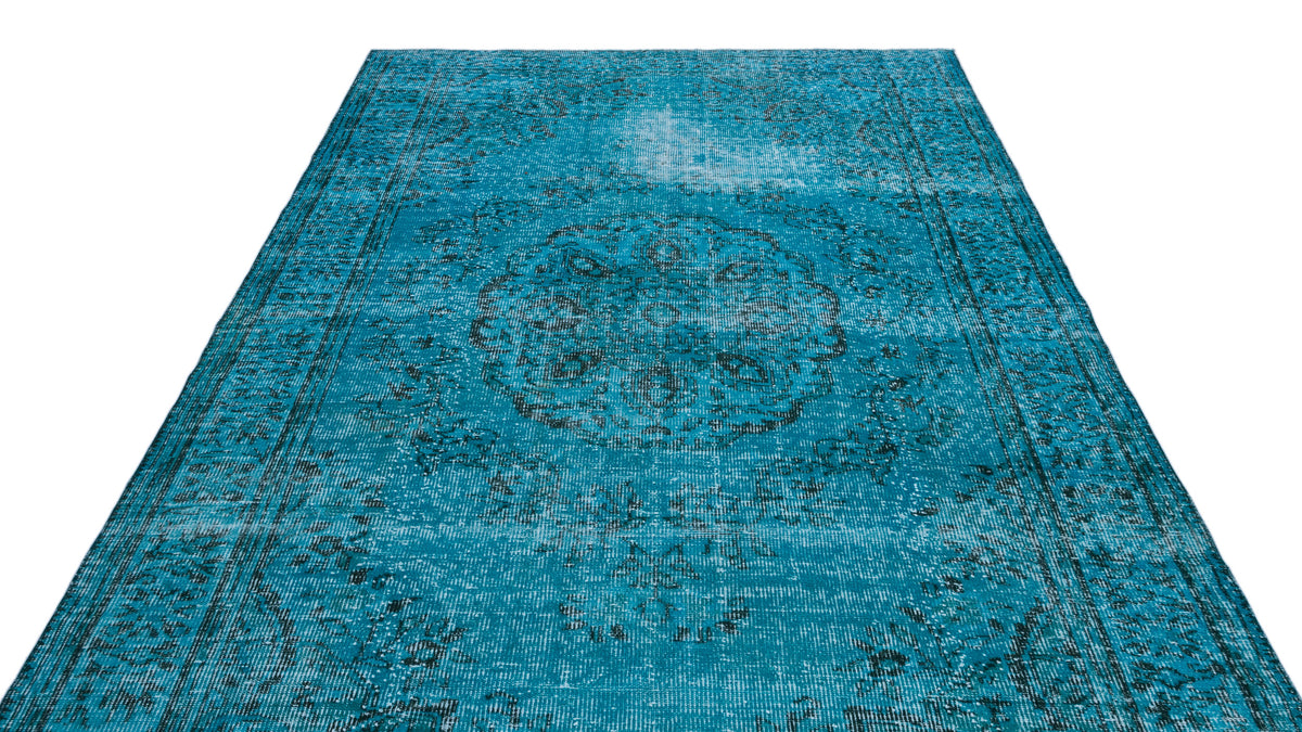 Distressed turquoise rug with a dark grey central medallion and traditional border pattern on a white background.