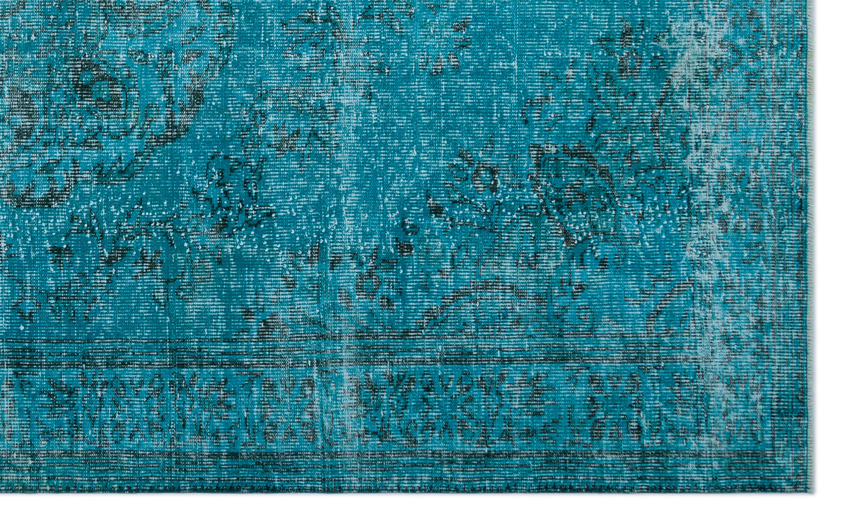 Teal and black distressed rug with a faded traditional floral medallion pattern.