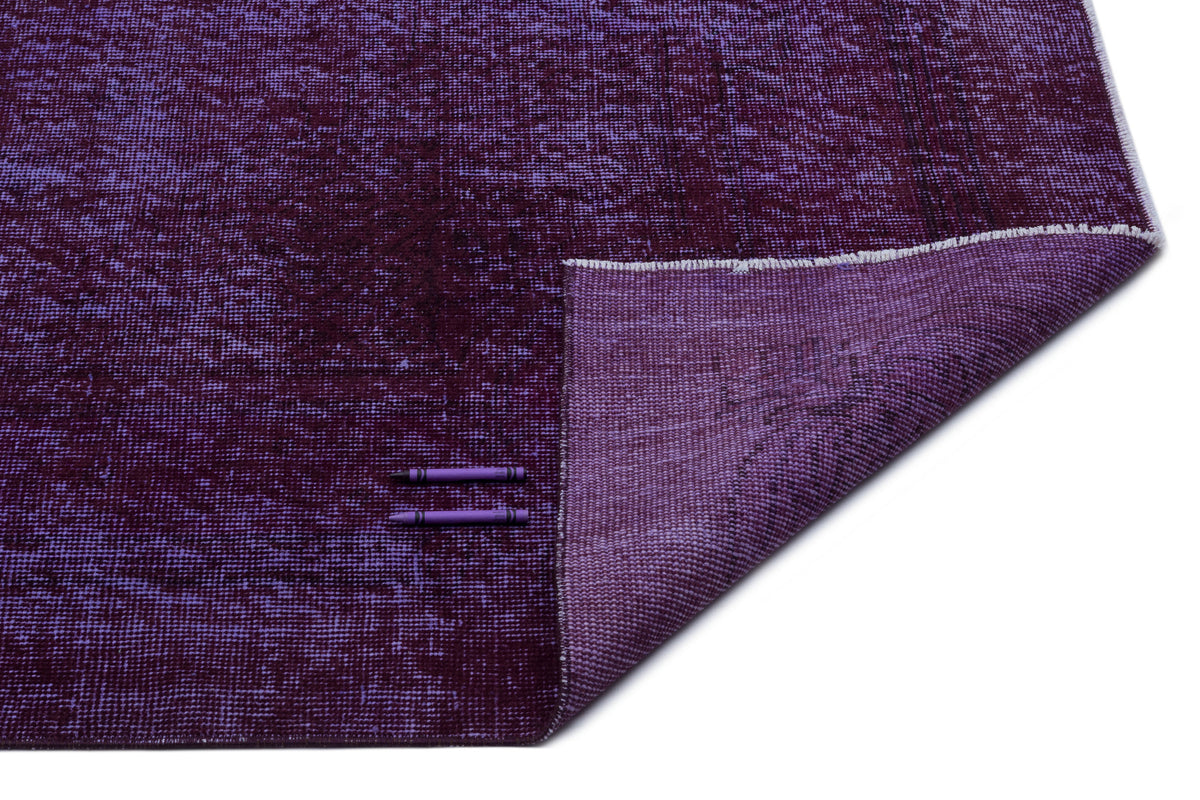 Deep purple distressed-texture rug with a folded corner, shown on a white background with two purple crayons.