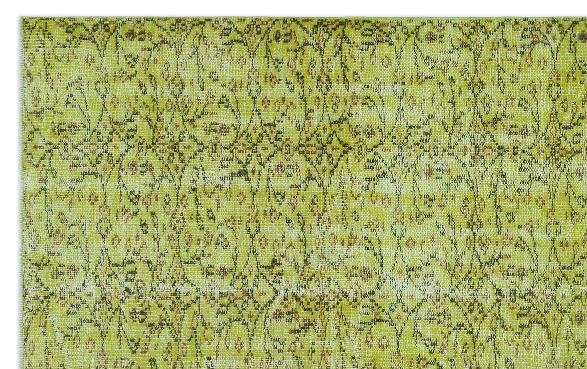 Chartreuse and brown distressed rug with a repeating vintage floral medallion pattern.