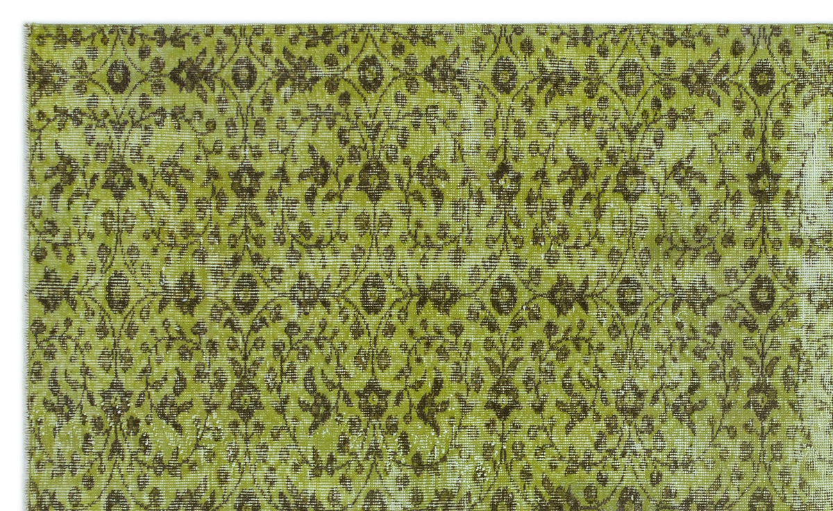 Chartreuse and dark brown vintage-style rug with a repeating floral medallion pattern and distressed texture.