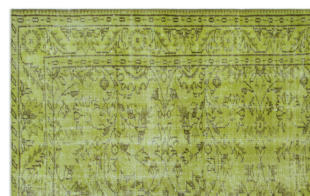 Chartreuse and brown vintage-style rug with a distressed floral medallion pattern and a geometric border.