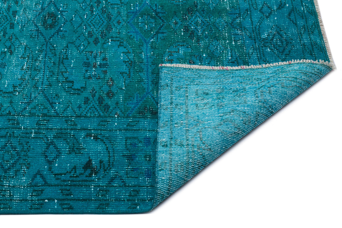 Teal distressed rug with a traditional medallion pattern, shown with a corner folded to reveal the woven backing.