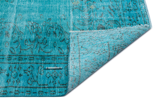 Load image 1 in gallery view. Turquoise distressed rug with a faded black floral pattern and a folded corner, isolated on a white background.