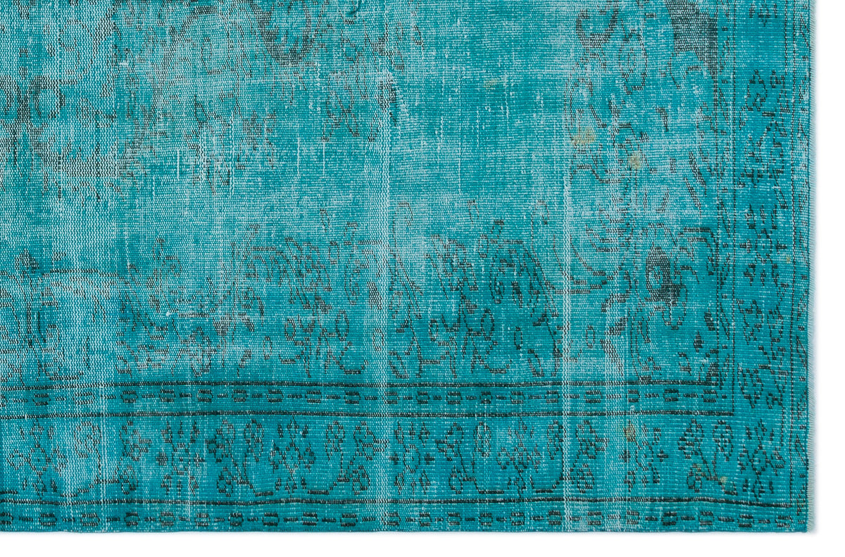Teal distressed rug with a faded traditional floral medallion pattern and a dark border.