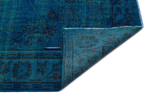 Load image 1 in gallery view. Teal and blue distressed rug with a traditional floral pattern, shown with a corner folded over on a white background.