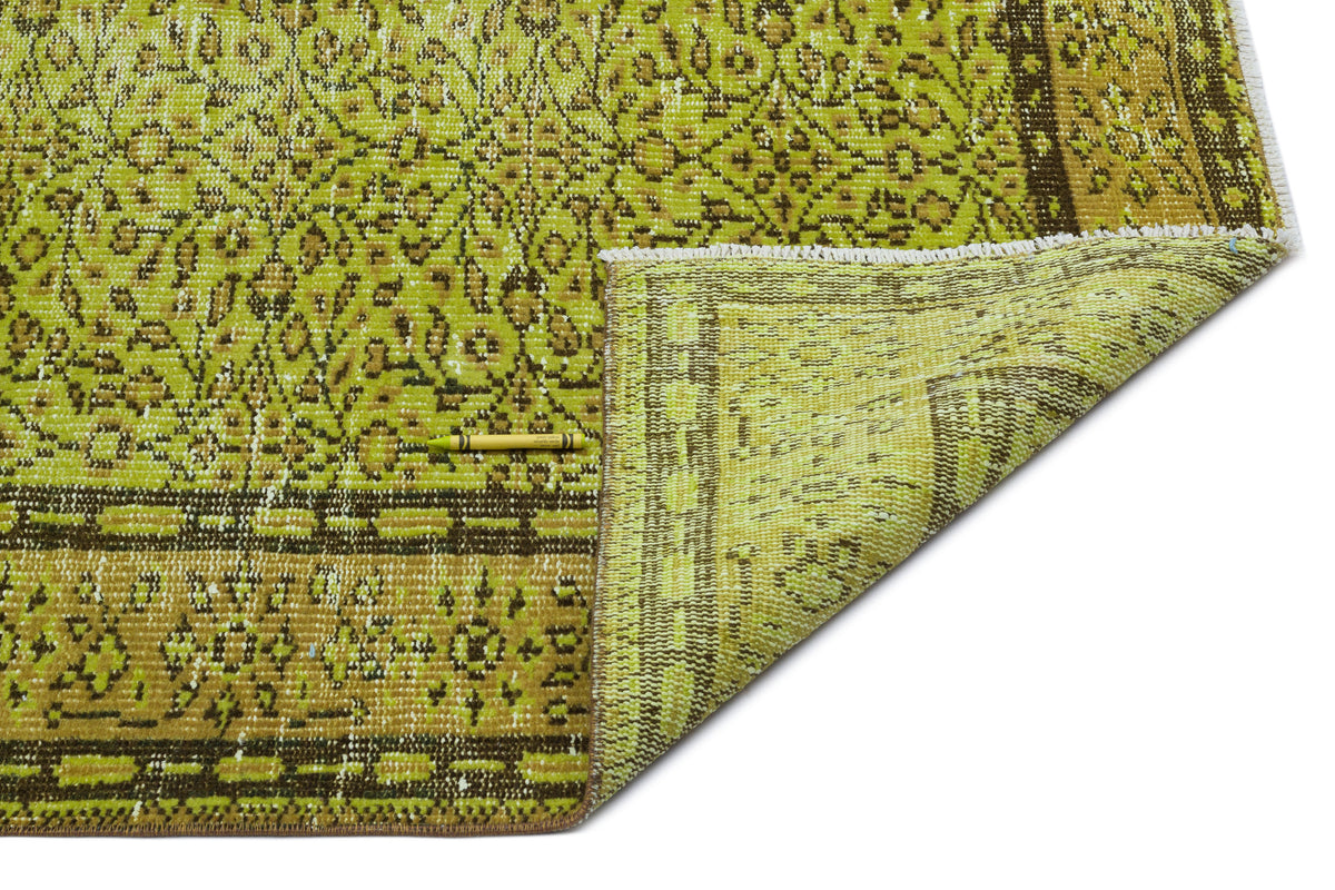 Chartreuse and brown vintage-style rug with a traditional floral pattern and a folded corner, on a white background.