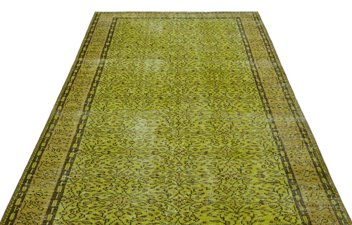 Chartreuse and brown vintage-style rug with a distressed floral medallion pattern and a geometric border.